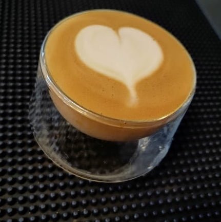 Kruve Imagine glass with a latte art heart on a bar mat 