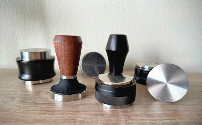 seven tampers on wooden table with white background